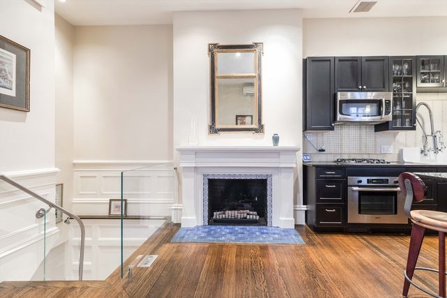 a living room with stainless steel appliances furniture a fireplace and wooden floor