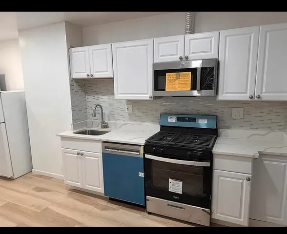 a kitchen with cabinets appliances and wooden floor