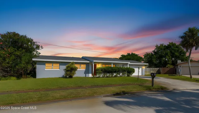 a front view of a house with a yard and potted plants