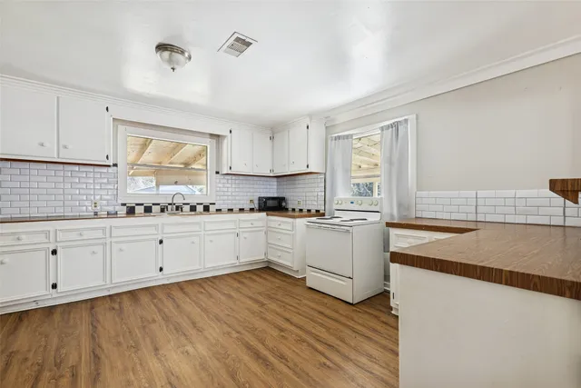a kitchen with granite countertop white cabinets and white appliances with wooden floor
