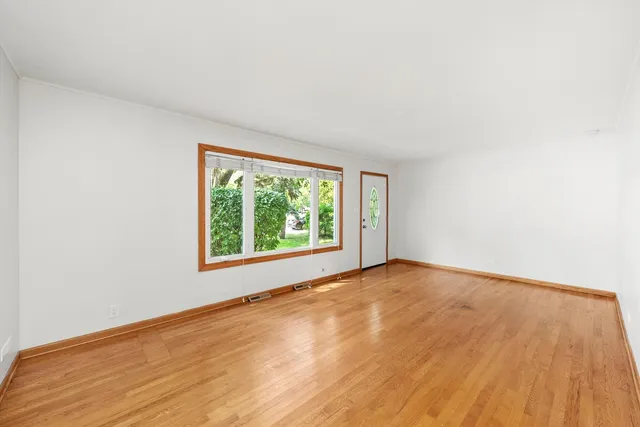a view of an empty room with wooden floor and closet