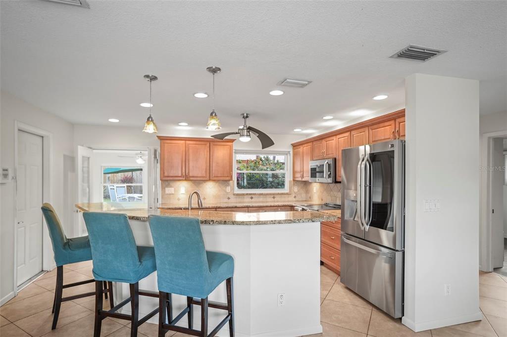 1215 Lazy Lake Road East Dunedin, FL 34698 - Photo 2 of 46 a kitchen with stainless steel appliances granite countertop dining table chairs and a refrigerator