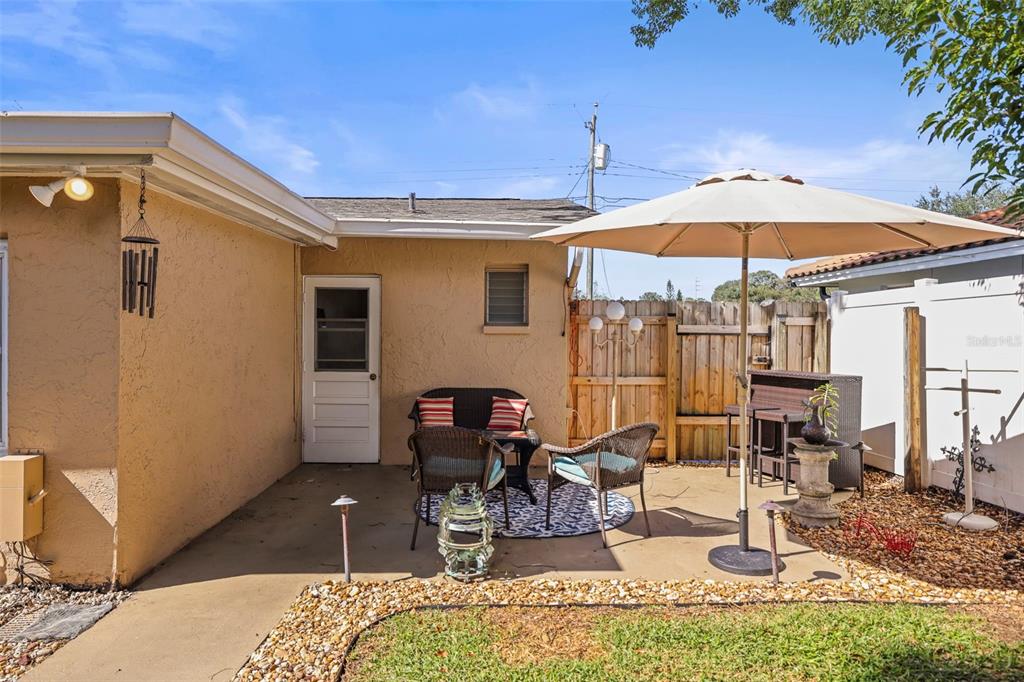1215 Lazy Lake Road East Dunedin, FL 34698 - Photo 22 of 46 a view of a patio with table and chairs under an umbrella