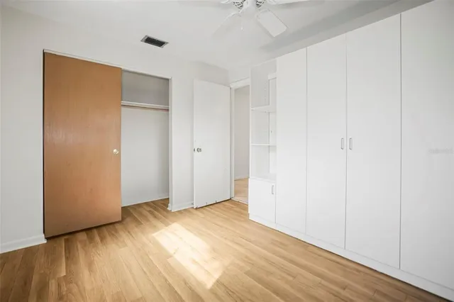 an empty room with wooden floor and closet area