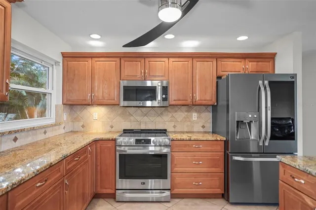 a kitchen with stainless steel appliances granite countertop a refrigerator a sink a stove and cabinets
