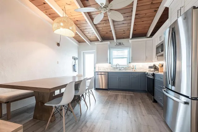 a kitchen with stainless steel appliances granite countertop a white refrigerator a sink dishwasher a dining table and chairs with wooden floor