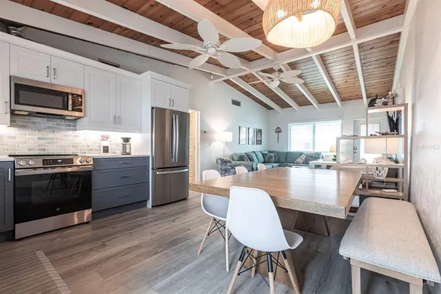 a large kitchen with stainless steel appliances granite countertop a stove refrigerator a dining table and chairs with wooden floor