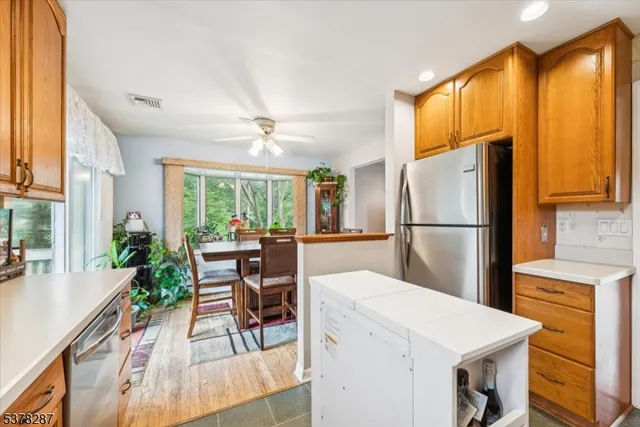 a kitchen with a refrigerator a stove a sink dishwasher and a dining table with wooden floor