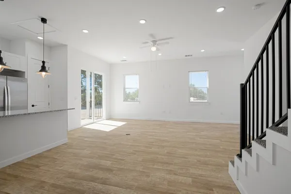 a view of an empty room with wooden floor and stairs