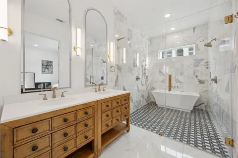 a spacious bathroom with a double vanity sink a large mirror and a shower