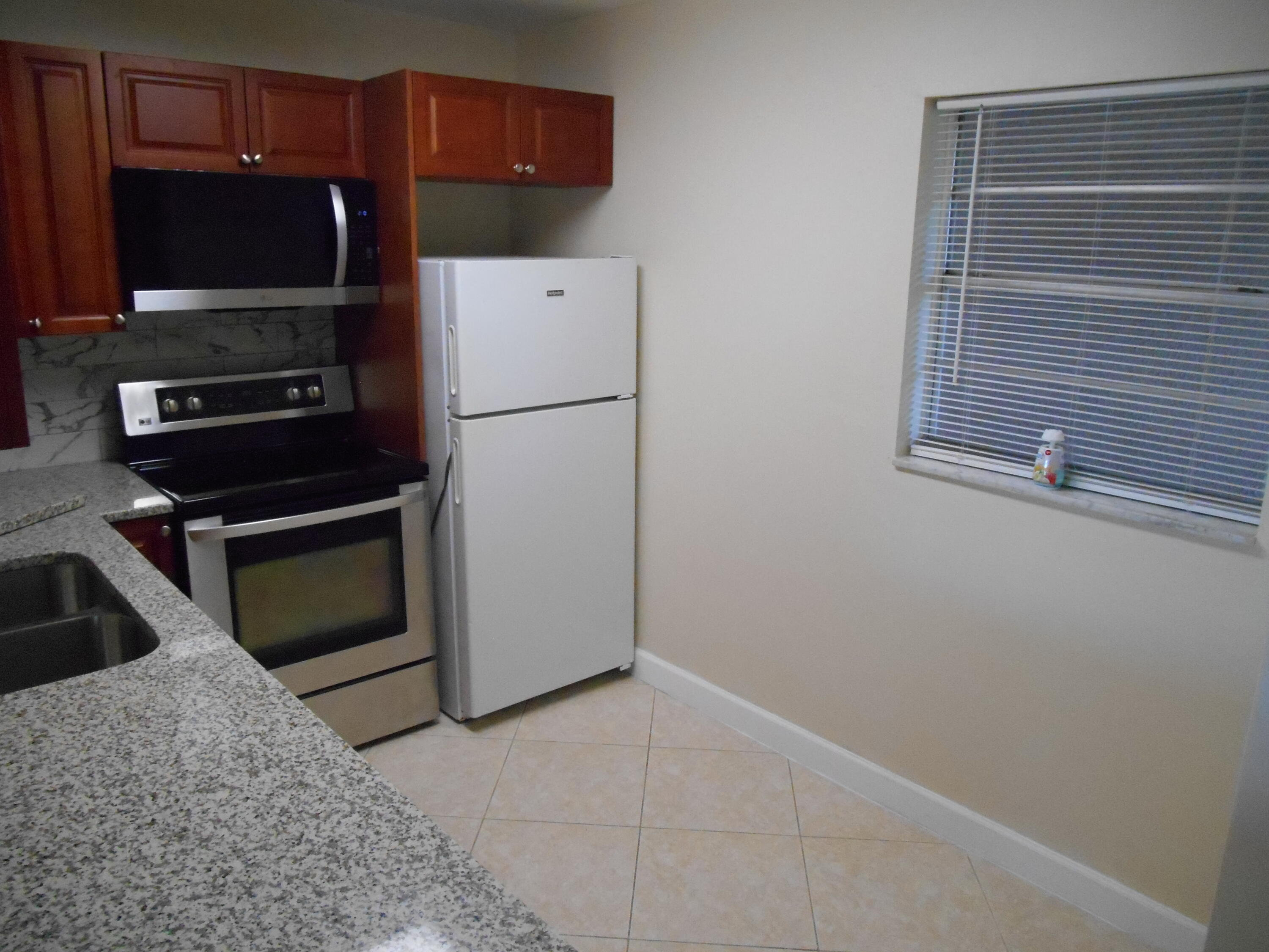 2615 Northeast 1st Court, Unit 301 Boynton Beach, FL 33435 - Photo 5 of 40 a kitchen with a refrigerator and a sink