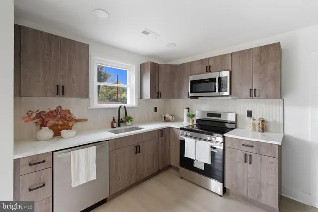 a kitchen with stainless steel appliances a sink stove top oven and cabinets