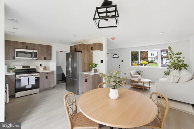 a kitchen with stainless steel appliances kitchen island granite countertop a refrigerator a stove a sink a dining table and chairs with wooden floor