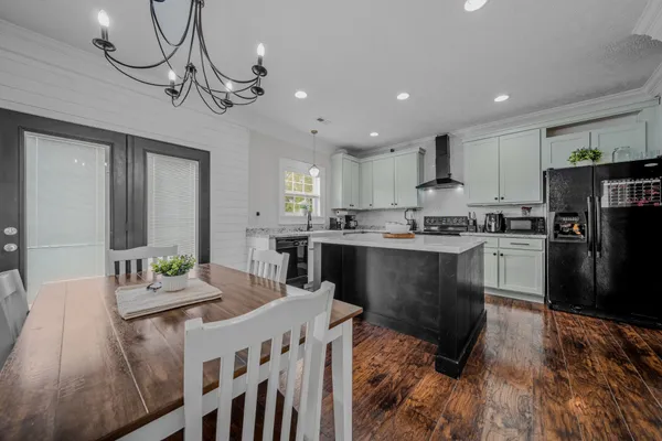 a kitchen with a refrigerator a stove top oven a sink dishwasher a dining table and chairs with wooden floor