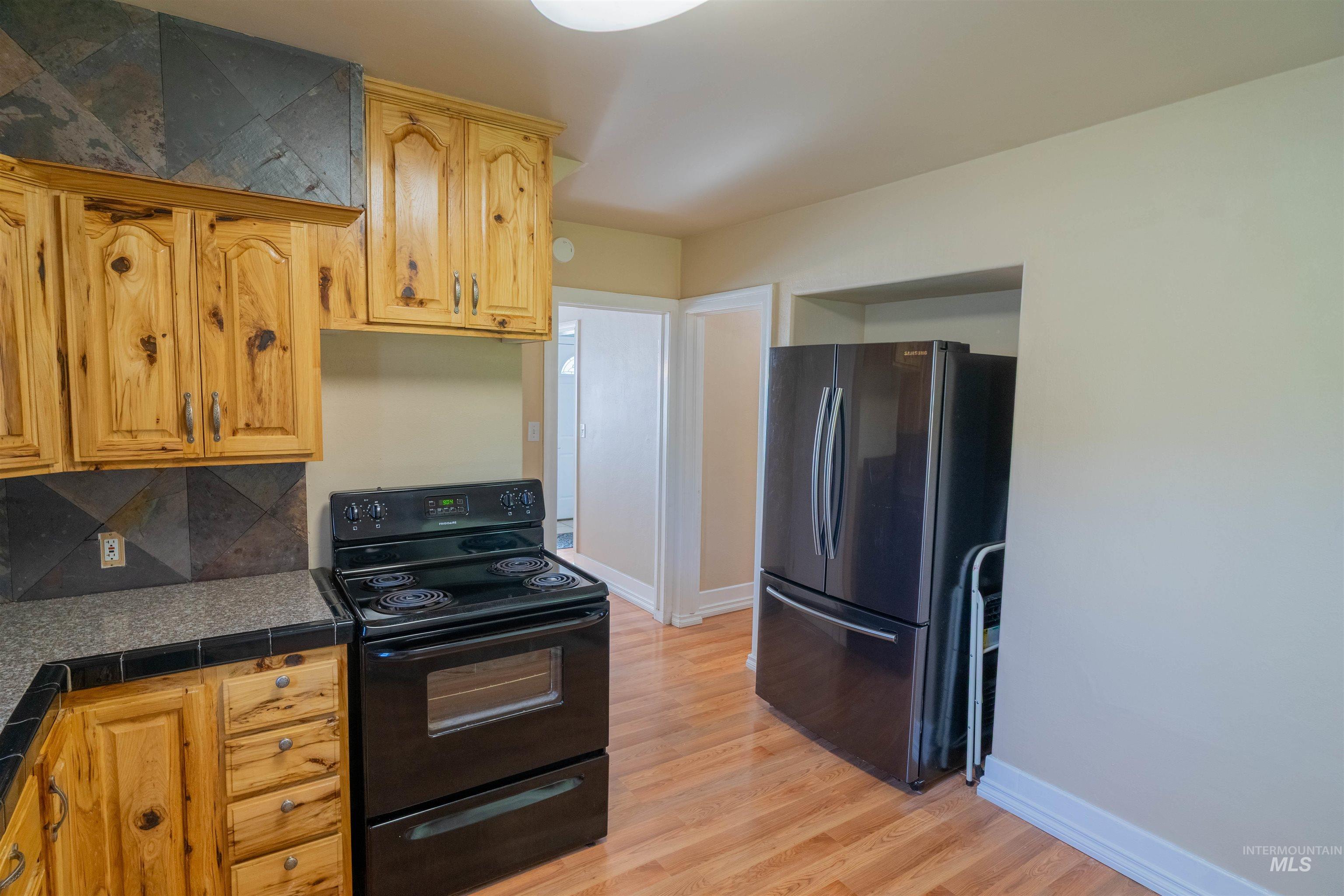 1212 14th Street Lewiston, ID 83501 - Photo 13 of 50 Kitchen with electric range, freestanding refrigerator, light wood-style flooring, backsplash, and tile countertops
