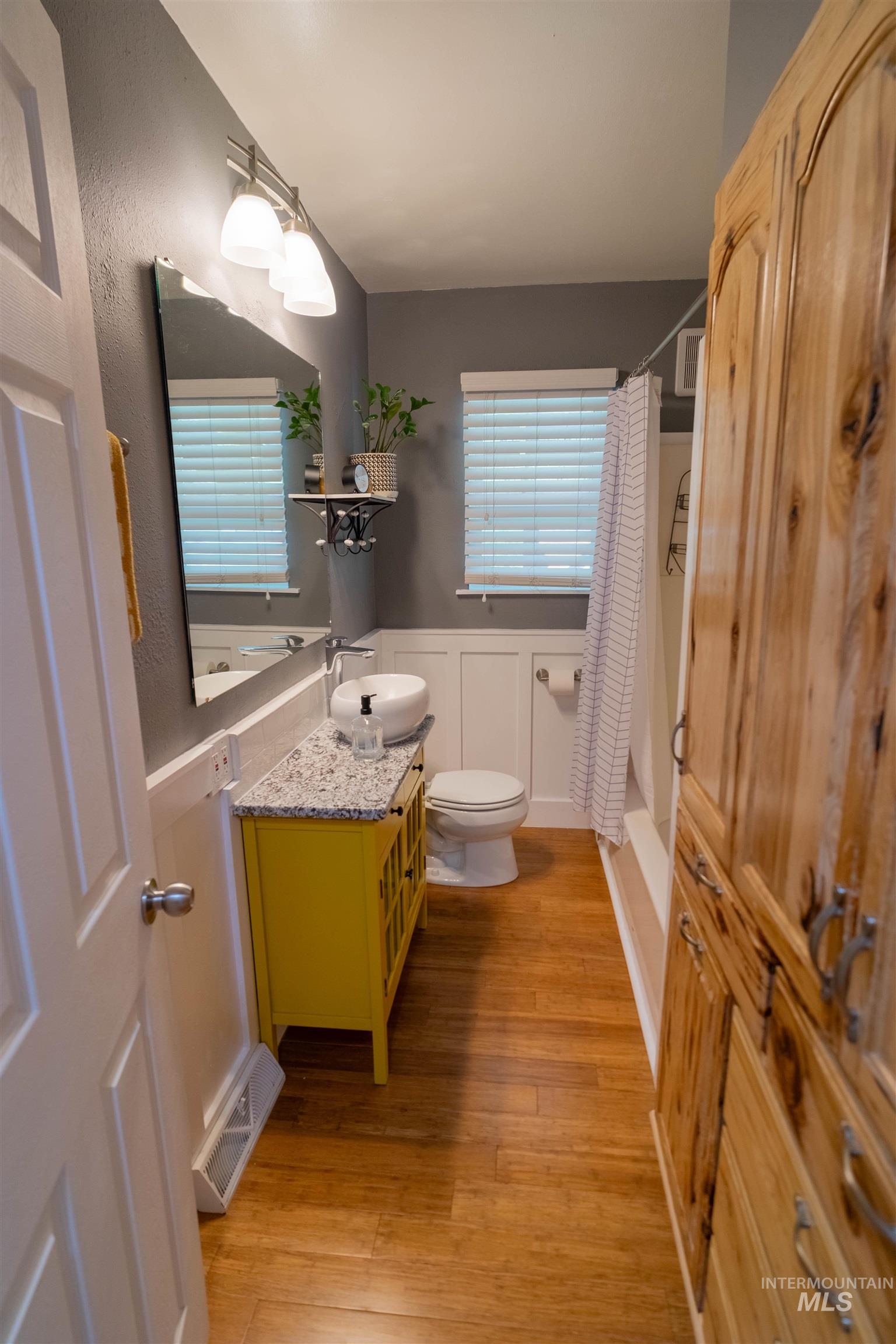 1212 14th Street Lewiston, ID 83501 - Photo 14 of 50 Full bath with wainscoting, vanity, light wood-type flooring, shower / tub combo, and a decorative wall
