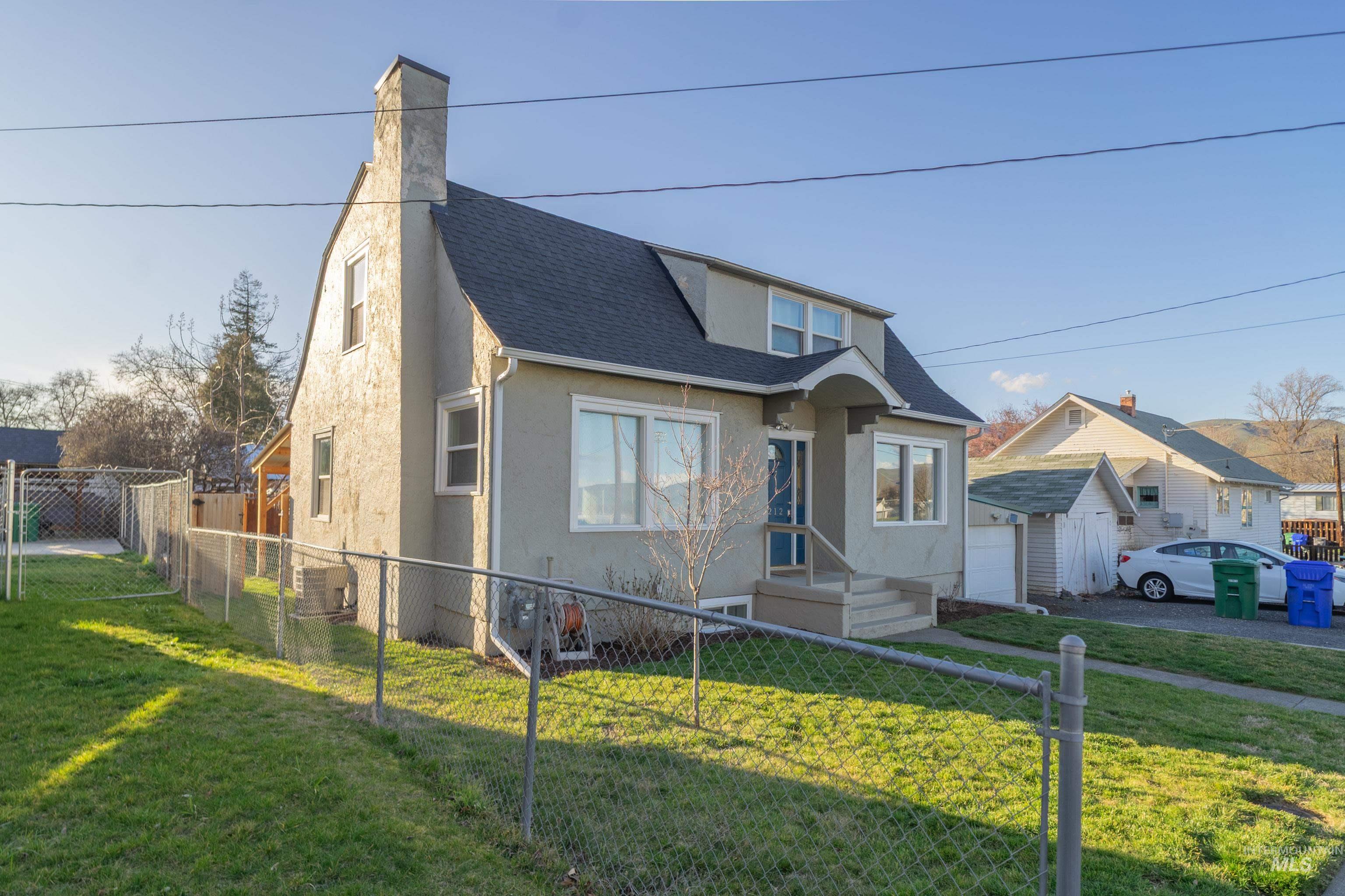 1212 14th Street Lewiston, ID 83501 - Photo 2 of 50 Bungalow-style house featuring roof with shingles, stucco siding, a fenced front yard, and a chimney