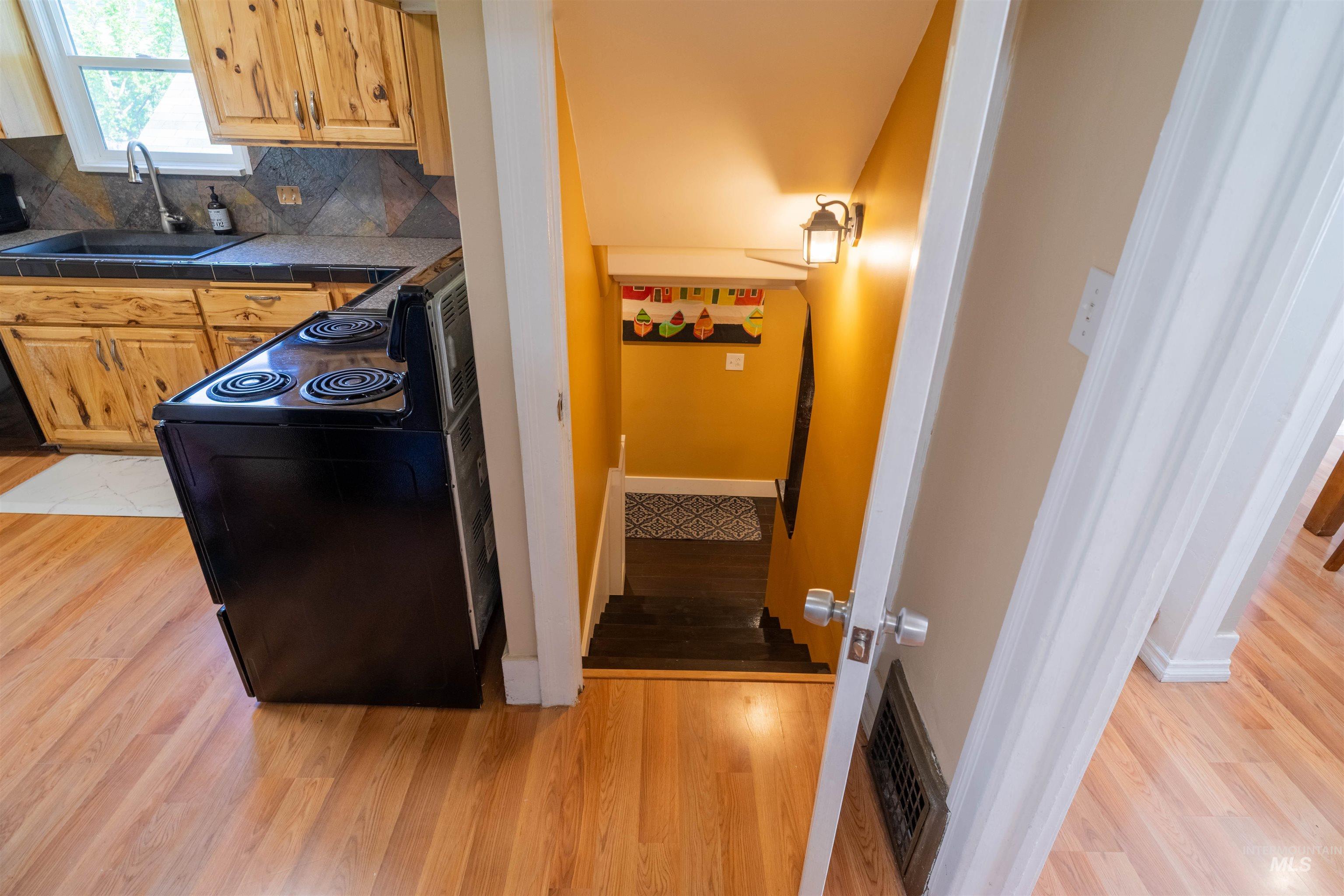 1212 14th Street Lewiston, ID 83501 - Photo 25 of 50 Kitchen featuring black / electric stove, backsplash, light wood-style flooring, and tile counters