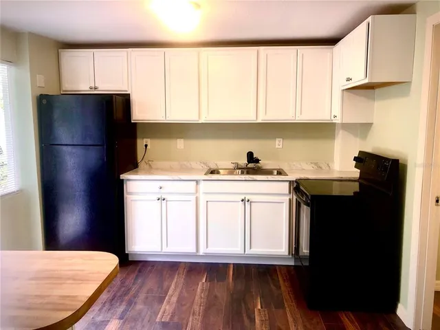 a kitchen with a refrigerator and white cabinets
