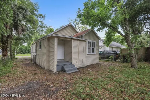a view of a house with a yard and large tree