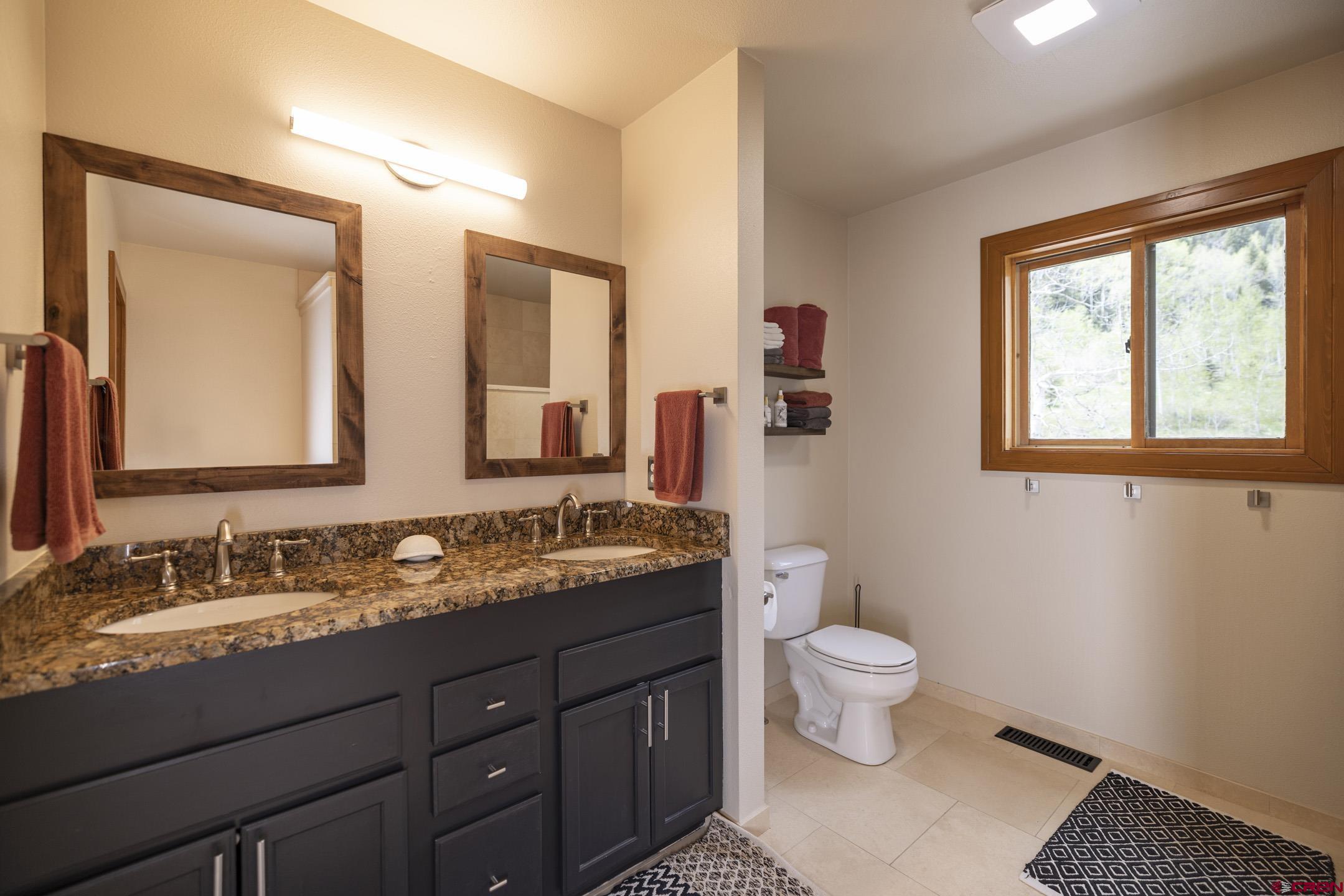 154 Falcon Ridge Road Durango, CO 81301 - Photo 24 of 42 a bathroom with a granite countertop sink a large mirror a toilet and a window