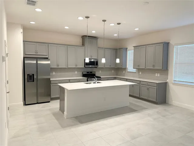 a large kitchen with stainless steel appliances lots of counter top space cabinets and a sink