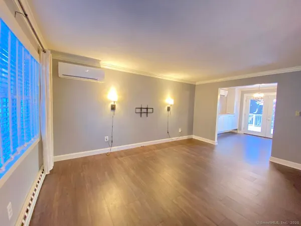 a view of an empty room with wooden floor and a window