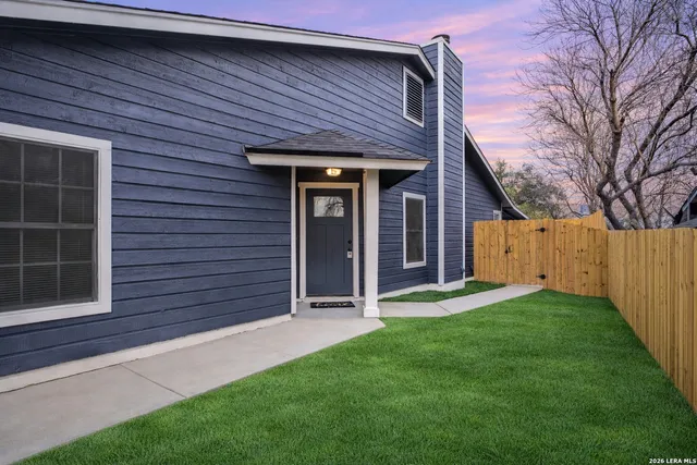 a view of a house with a yard and wooden fence