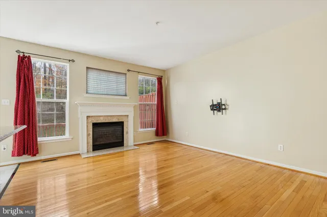 a view of empty room with a fireplace and wooden floor