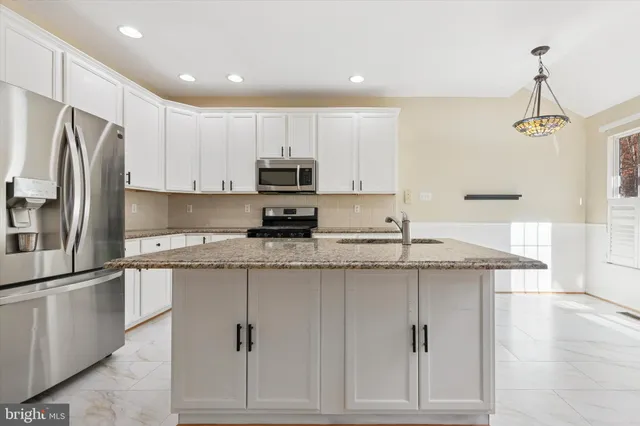 a kitchen with stainless steel appliances granite countertop a refrigerator a stove and a sink