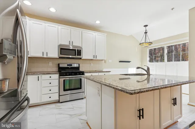 a kitchen with granite countertop a sink stainless steel appliances and white cabinets