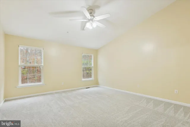 an empty room with windows and ceiling fan