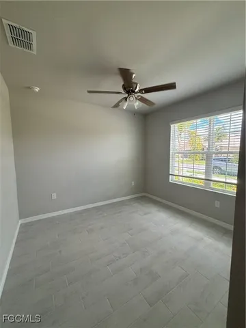 an empty room with a window and a fan