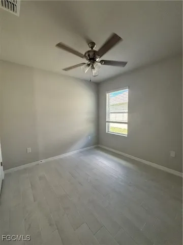 en empty room with windows and ceiling fan