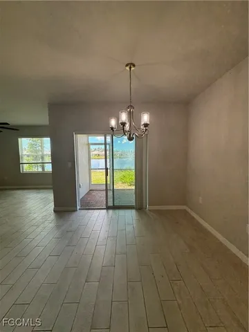 an empty room with wooden floor and chandelier