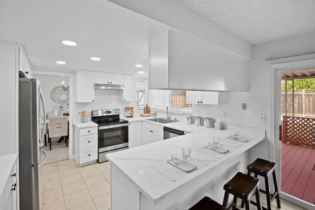 a kitchen that has a lot of white cabinets and stainless steel appliances