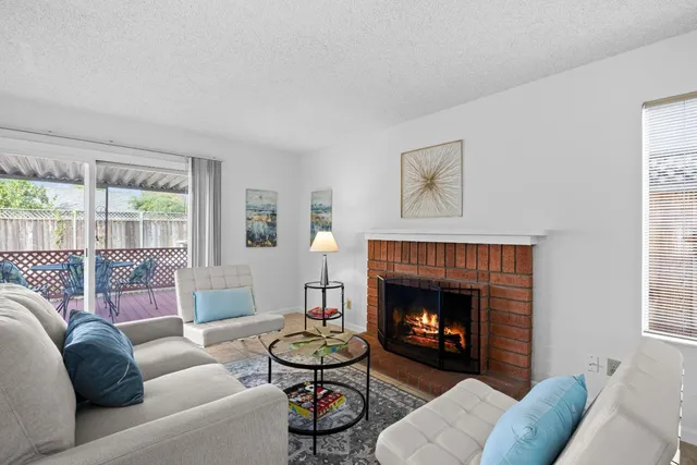 a living room with furniture a fireplace and a large window