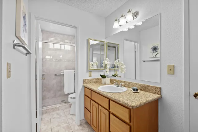 a bathroom with a granite countertop sink a large mirror and a shower