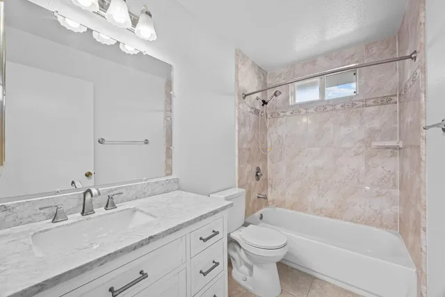 a bathroom with a granite countertop sink a toilet and shower