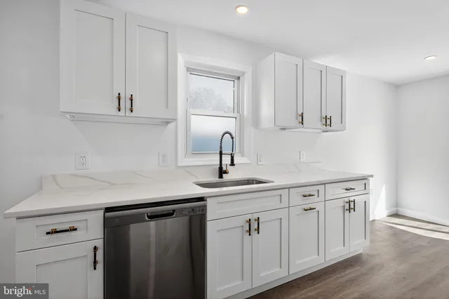 a kitchen with white cabinets a sink and dishwasher