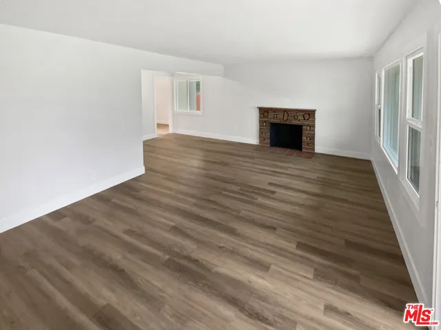 a view of empty room with wooden floor and fireplace