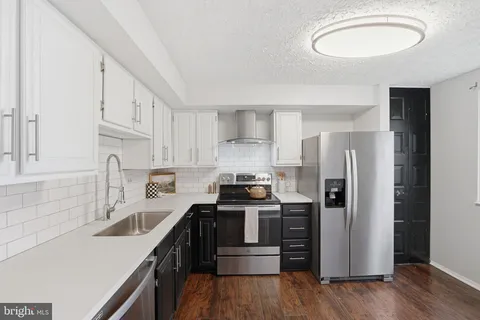 a kitchen with stainless steel appliances a sink a stove a refrigerator and cabinets