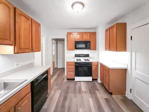 a kitchen with stainless steel appliances a stove top oven a sink dishwasher and a refrigerator with wooden floor