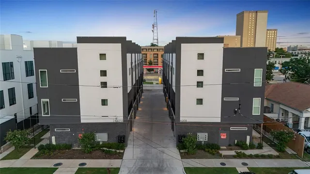 a front view of a multi story residential apartment building with yard and parking space