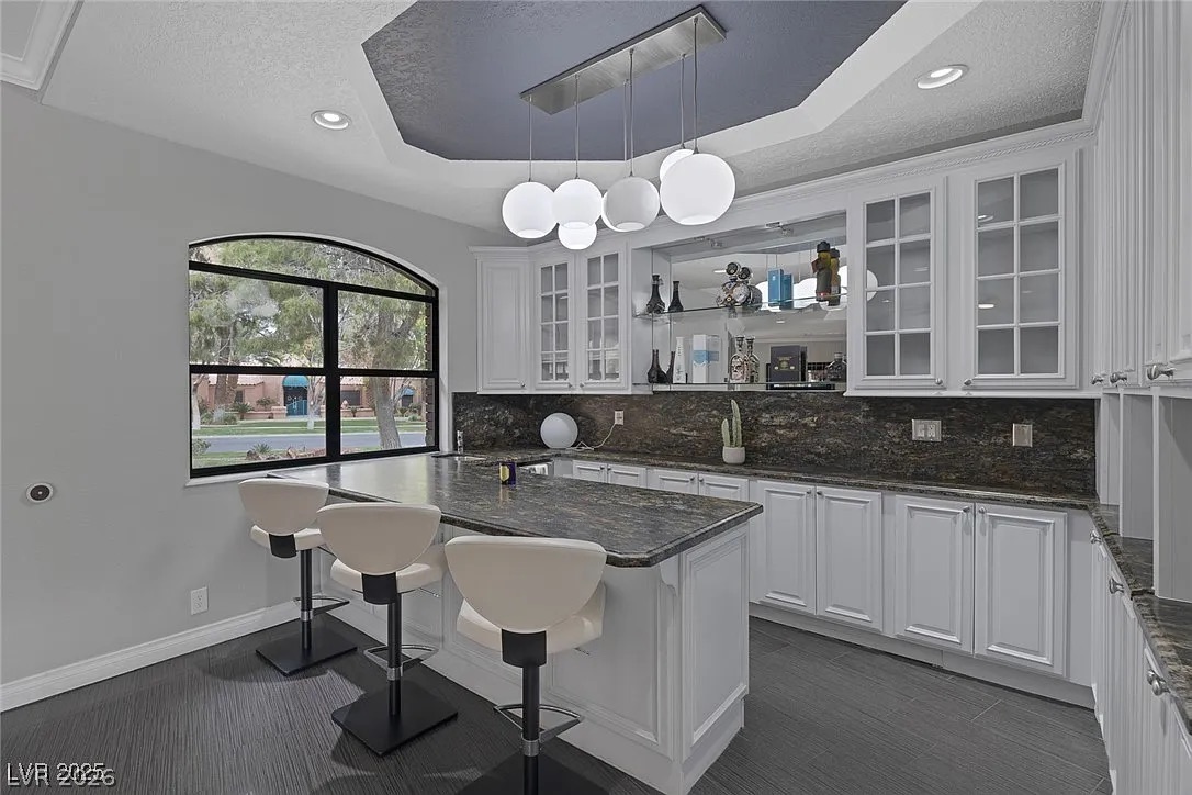 9 Quail Run Road Henderson, NV 89014 - Photo 15 of 57 A well-appointed kitchen features a large breakfast bar with seating, rich granite countertops, and sleek white cabinetry.