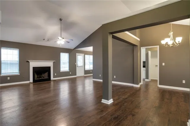 a view of an empty room with wooden floor and a fireplace