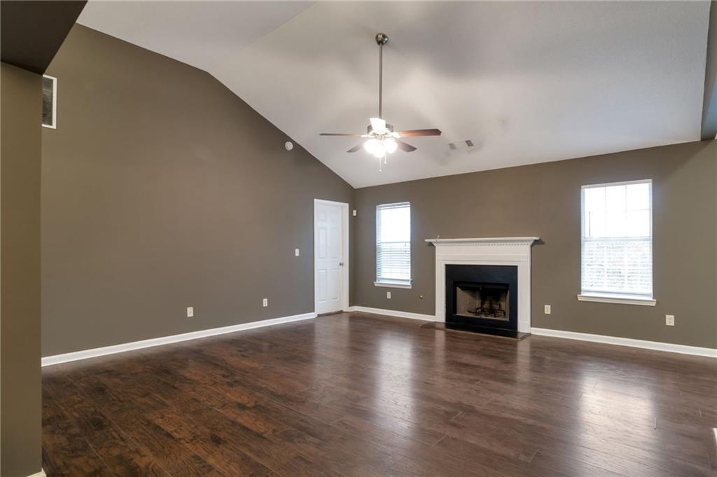 4598 Jackam Ridge Court Lithonia, GA 30038 - Photo 5 of 25 an empty room with wooden floor fireplace and windows