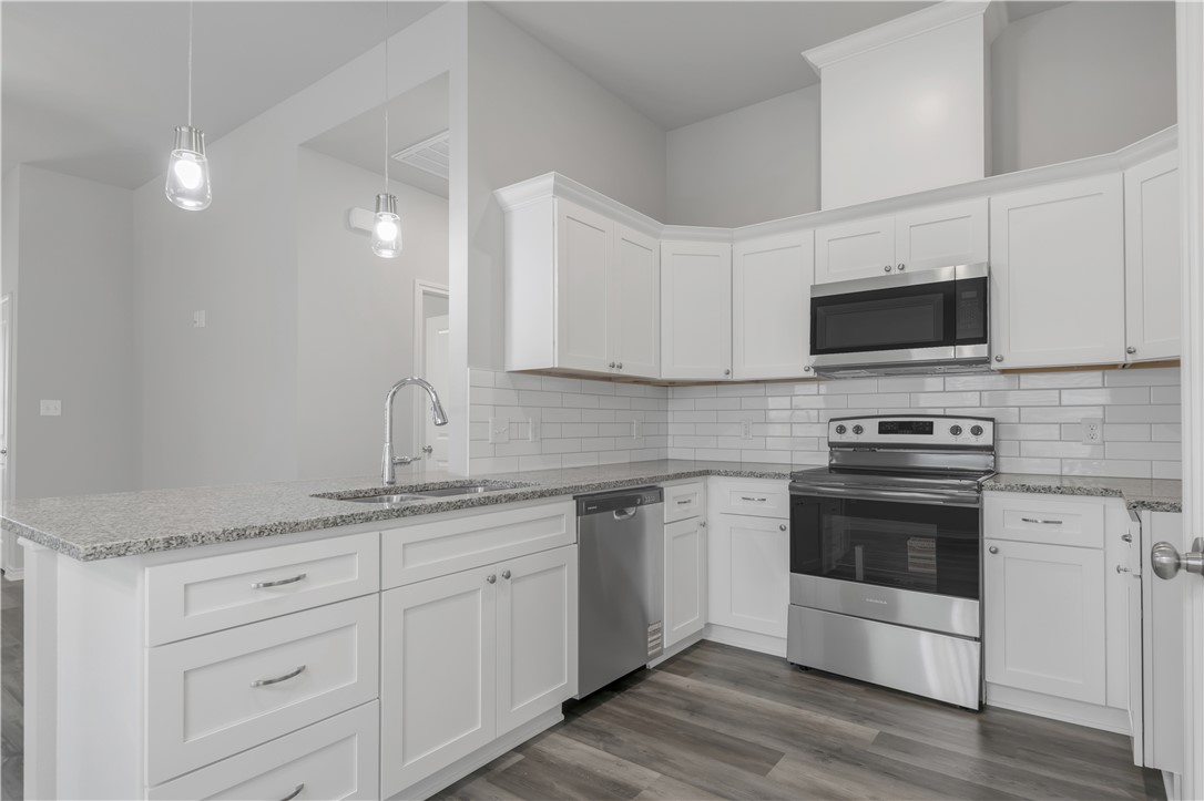 1805 Pin Oak Street Bryan, TX 77803 - Photo 11 of 20 Kitchen with stainless steel appliances, a peninsula, white cabinetry, and decorative backsplash