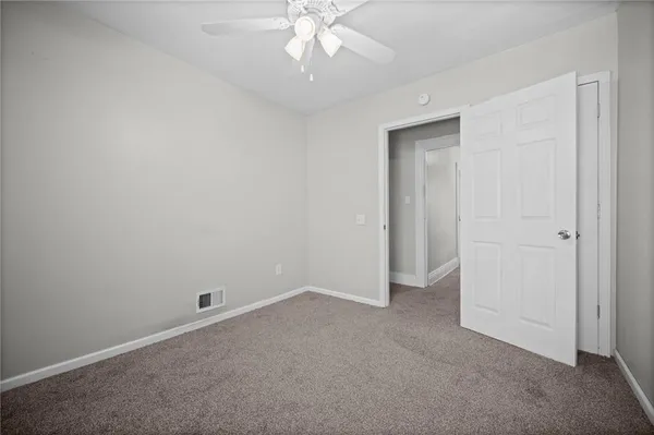 an empty room with a ceiling fan and carpet