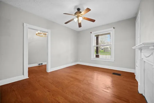 an empty room with windows and ceiling fan